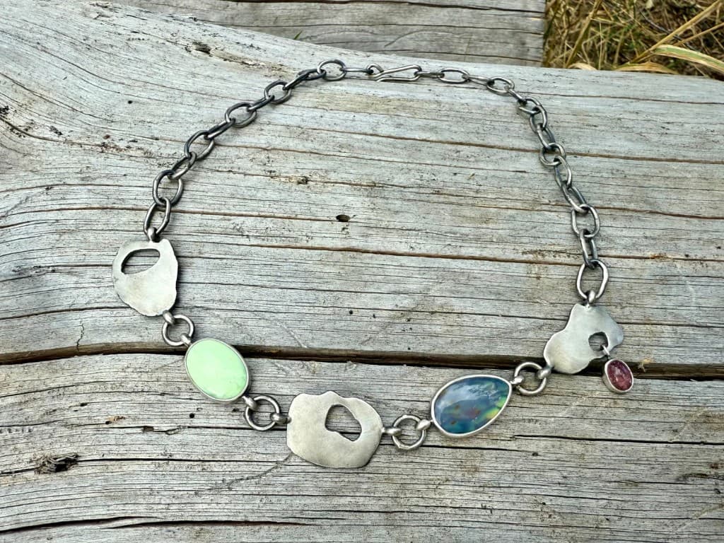 Handmade silver necklace with stones arranged on weathered driftwood