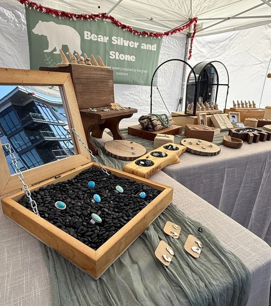 Market tent display with sage green Bear Silver & Stone banner and jewelry on natural wood